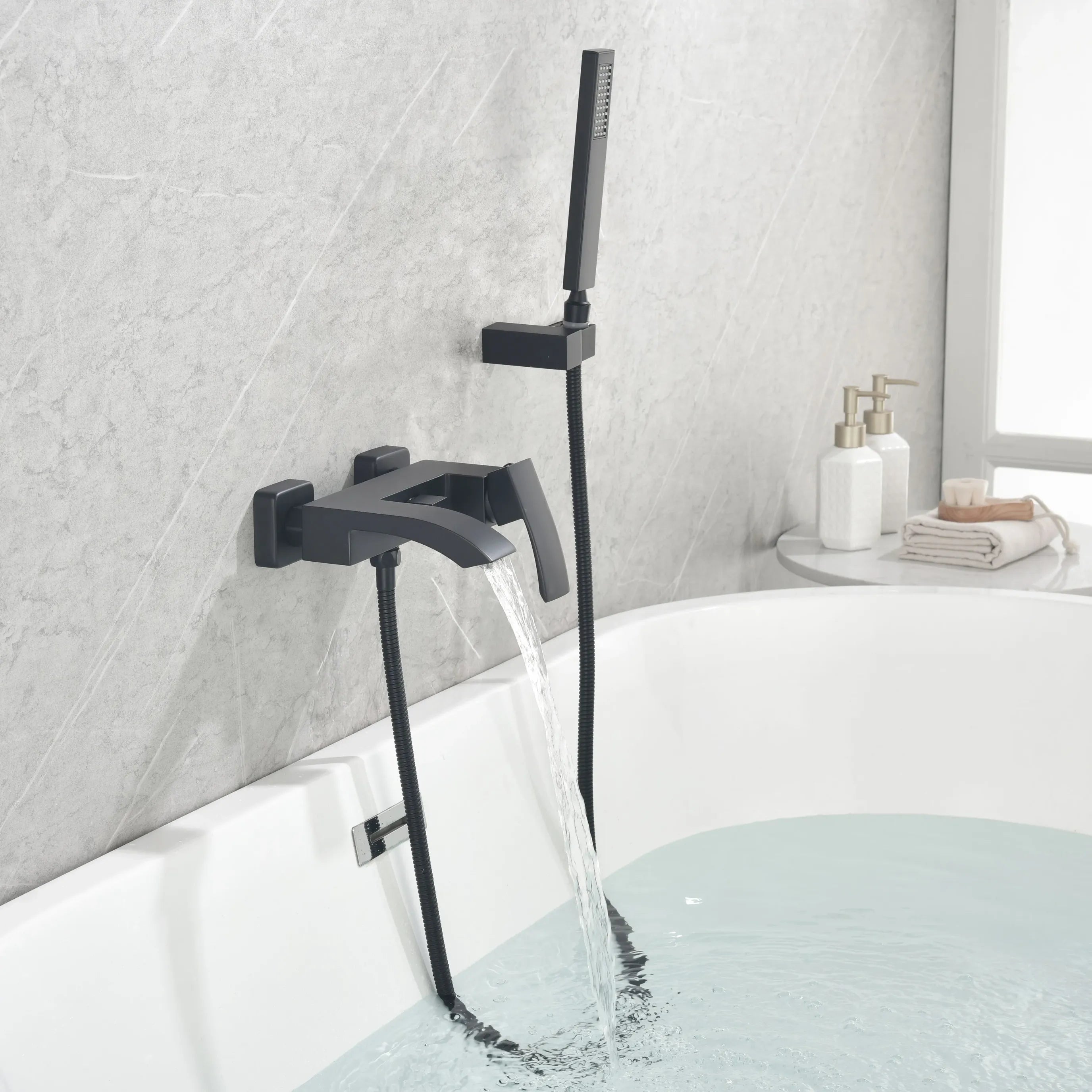 AURELIA matte black wall-mounted bathtub faucet with hand shower installed beside a modern bathtub.