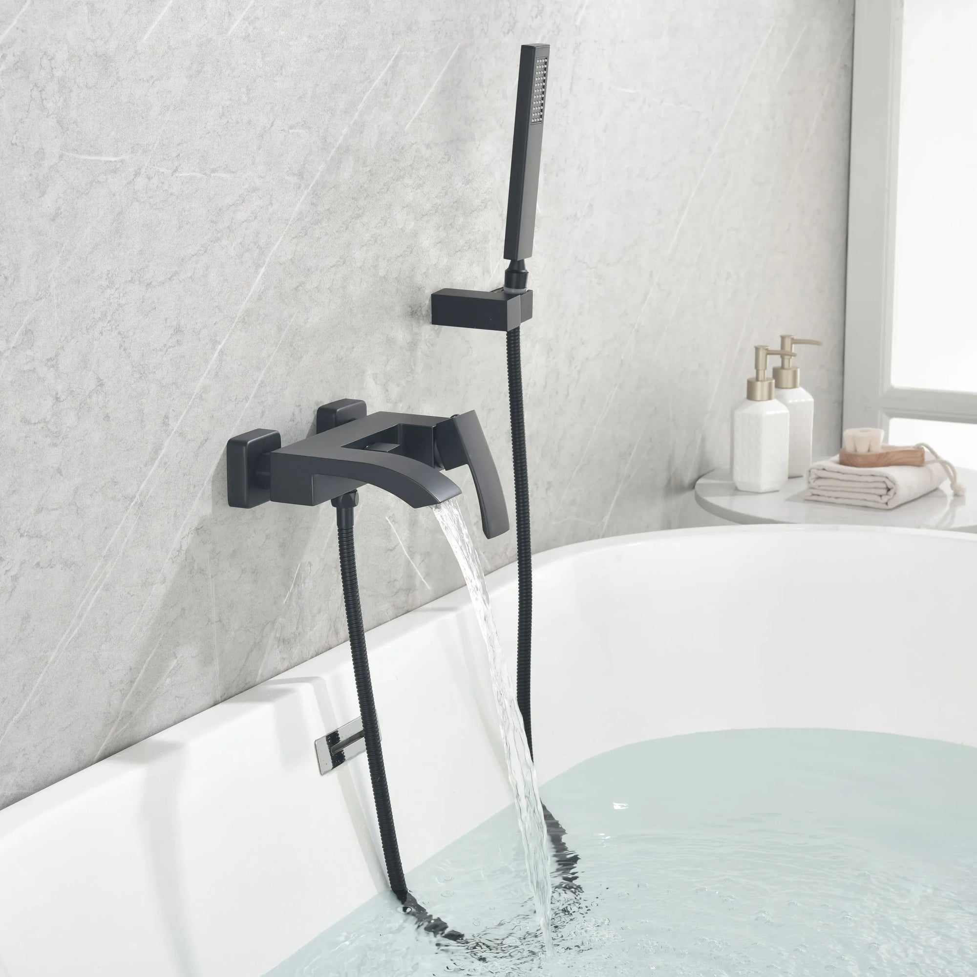 AURELIA matte black wall-mounted bathtub faucet with hand shower installed beside a modern bathtub.