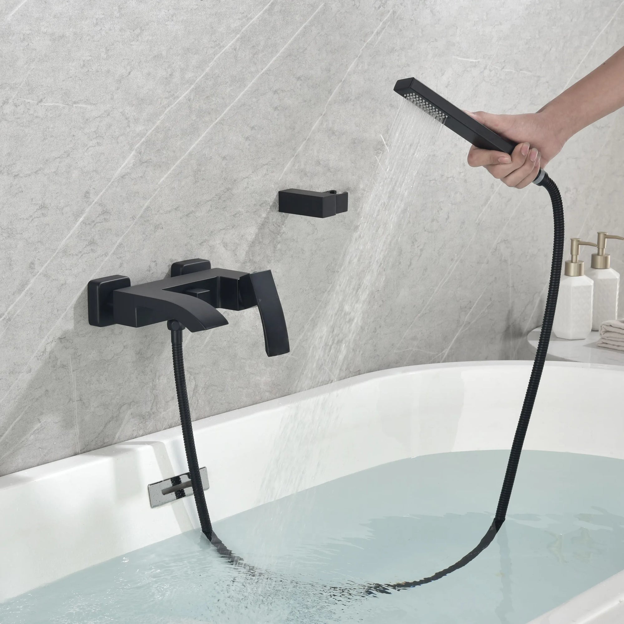 Matte black handheld shower in use for flexible bathtub rinsing.