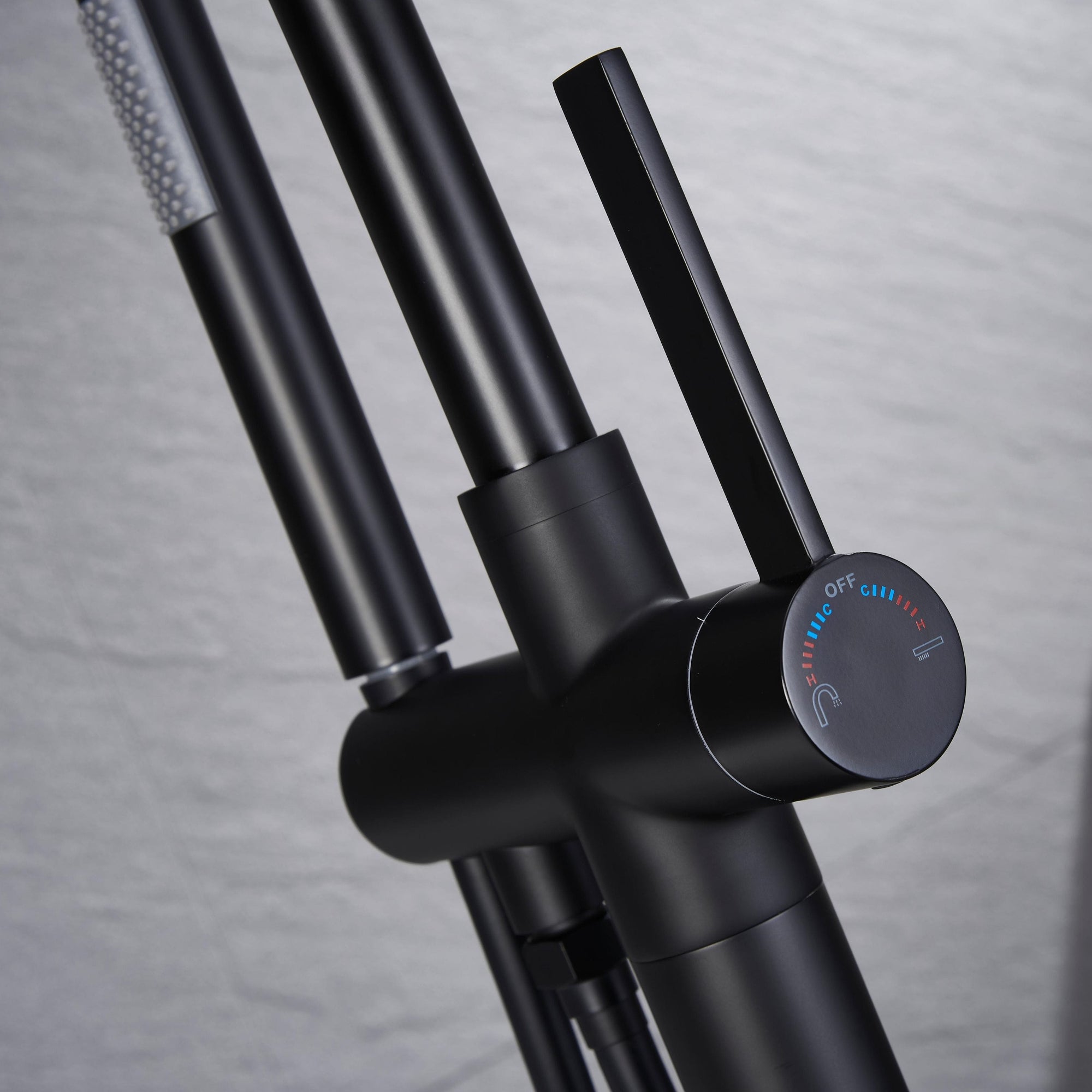 Close-up of Black Freestanding Tub Faucet handle with hot and cold indicators.