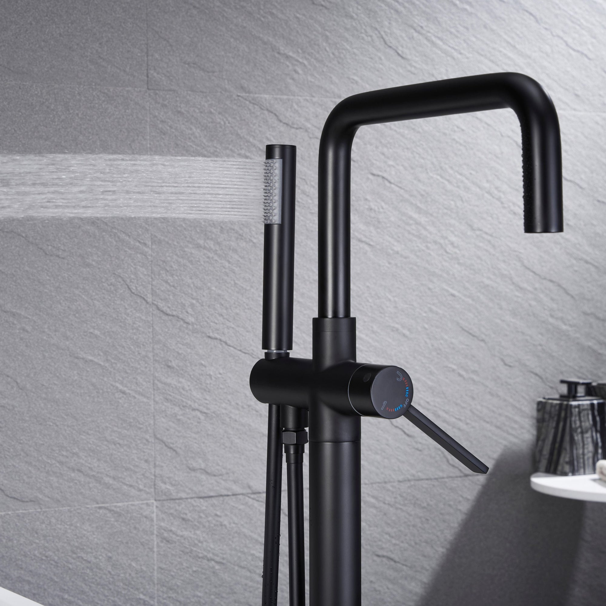 Black Freestanding Tub Faucet with handheld shower spraying water.