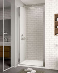 Semi-frameless pivot shower door in chrome finish shown open in modern white tiled bathroom.