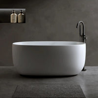 Lissome 47-inch modern freestanding bathtub with black tub faucet in a minimalist grey bathroom setting.